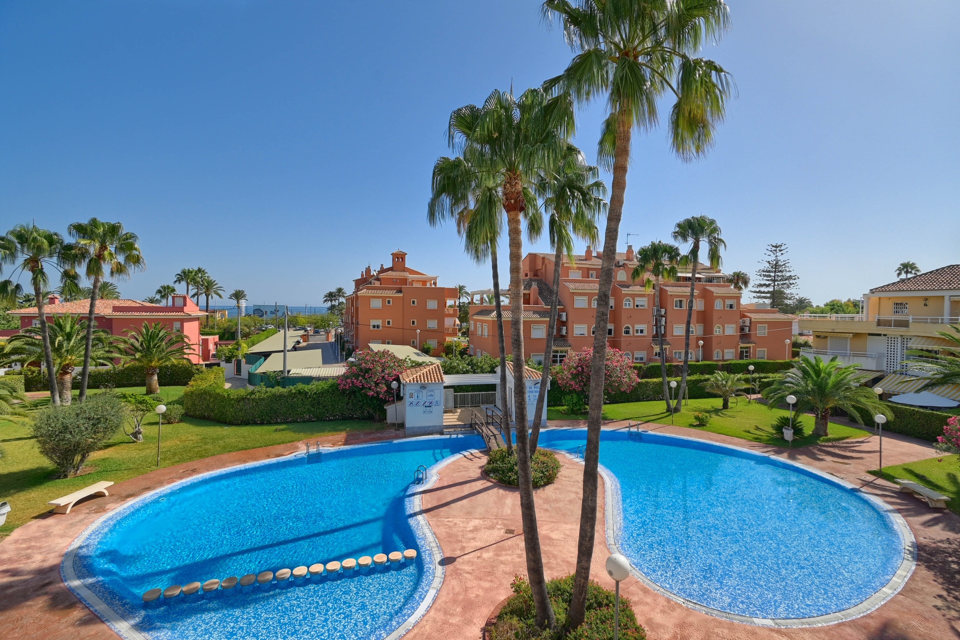 Community pool and gardens with sea in the distance